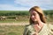 Young, beautiful blonde woman in a yellow dress, with a daisy in her hand, in the middle of the countryside, calm and relaxed.