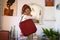 Young, beautiful, bohemian Latina, wearing a red beret on her head and a red vintage suitcase, looking happily at the camera for