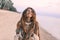 Young beautiful boho woman portarait with traditional ornament on the beach at sunset