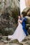 Young and beautiful bride with her elegant groom dancing in weathered rock cleft