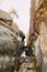 Young and beautiful bride with her elegant groom posing in weathered rock cleft