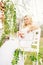 Young and beautiful bride sitting on a white swing in a spring g