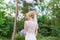 Young beautiful bride walk in green forest with bridal bouquet in white wedding dress