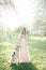 Young beautiful bride in wedding dress with greyhound outdoors