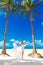 Young beautiful bride in white wedding dress under the palm tree