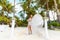 Young beautiful bride in white wedding dress under the palm tree