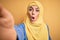 Young beautiful brunette arab woman wearing islamic hijab make selfie by camera scared in shock with a surprise face, afraid and