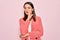 Young beautiful brunette businesswoman wearing elegant jacket over isolated pink background hand on mouth telling secret rumor,