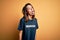 Young beautiful brunette girl doing volunteering wearing t-shirt with volunteer message word sticking tongue out happy with funny