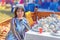 A young beautiful brunette girl in a Kazakh national dress sells tea sets at the fair