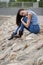 Young beautiful brunette girl sitting on the rocks on the river