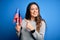 Young beautiful brunette patriotic woman holding american flag celebrating 4th of july very happy pointing with hand and finger