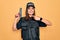 Young beautiful brunette policewoman wearing police uniform bulletproof and cap using gun very happy pointing with hand and finger