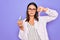 Young beautiful brunette scientist woman wearing coat and glasses holding test tube with angry face, negative sign showing dislike