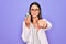 Young beautiful brunette scientist woman wearing coat and glasses holding test tube pointing with finger to the camera and to you,