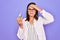 Young beautiful brunette scientist woman wearing coat and glasses holding test tube stressed and frustrated with hand on head,