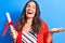 Young beautiful brunette smart woman holding graduated degree diploma over blue background celebrating achievement with happy