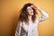 Young beautiful brunette woman with curly hair and piercing wearing shirt and glasses very happy and smiling looking far away with