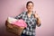 Young beautiful brunette woman doing chores holding wicker basket with clothes happy with big smile doing ok sign, thumb up with