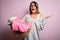 Young beautiful brunette woman doing housework holding wicker basket with clothes very happy and excited, winner expression