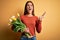 Young beautiful brunette woman holding bouquet of tulips flowers over yellow background crazy and mad shouting and yelling with