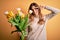 Young beautiful brunette woman holding bouquet of yellow tulips over isolated background Doing peace symbol with fingers over