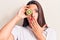 Young beautiful brunette woman holding kiwi covering mouth with hand, shocked and afraid for mistake