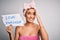 Young beautiful brunette woman holding paper with love yourself message after shower stressed with hand on head, shocked with