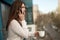 Young beautiful brunette woman manager having phone conversation on the office balcony while drinking her coffee, office routine