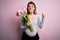 Young beautiful brunette woman pregnant expecting baby holding bouquet of tulips annoyed and frustrated shouting with anger, crazy