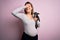 Young beautiful brunette woman pregnant expecting baby holding chihuahua puppy stressed with hand on head, shocked with shame and