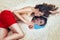 Young beautiful brunette woman with red fabric on the thighs lying on the beach. The reflection in the mirror.