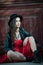 Young beautiful brunette woman with red short dress and black hat posing sensual in vintage scenery. Romantic mysterious lady