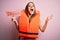 Young beautiful brunette woman wearing lifejacket holding paper with danger message very happy and excited, winner expression