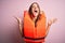 Young beautiful brunette woman wearing orange lifejacket over isolated pink background celebrating mad and crazy for success with
