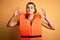 Young beautiful brunette woman wearing orange safe lifejacket over yellow background relax and smiling with eyes closed doing