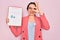 Young beautiful business woman with blue eyes wearing glasses holding clipboard with happy face smiling doing ok sign with hand on