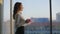 Young beautiful business woman drinking coffee standing by panoramic window in european modern office