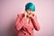 Young beautiful businesswoman with blue fashion hair wearing jacket over pink background covering ears with fingers with annoyed