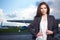 Young beautiful businesswoman in front of airplane.