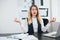 Young beautiful businesswoman manager with red lipstick works in her modern office, looks relaxed sitting in peaceful yoga