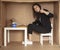 Young beautiful businesswoman sits in office cardboard box and shows thumb up
