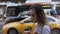 Young beautiful businesswoman standing near the road, drinking coffee and using the smartphone. Female waiting for taxi.