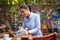 Young beautiful caucasian adult female sitting in outdoor cafe, smiling, looking at her laptop, typing. online communication