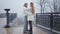 Young beautiful Caucasian couple dancing on the bridge in autumn park. Handsome man in stylish white shirt and vest and