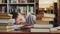 Young beautiful caucasian female student is sleeping on table surrounded by piles of books and papers, phone is lieing