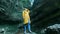 Young beautiful caucasian girl traveler in a yellow rain coat walks through a tropical cave. Looking for adventure in