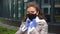 Young beautiful caucasian puts a black face mask over her face to protect herself during a pandemic wearing blue gloves