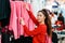 A young beautiful Caucasian smiling woman choosing clothes in a store. Side view. The concept of shopping and consumerism