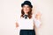 Young beautiful caucasian woman holding banner with blank space doing ok sign with fingers, smiling friendly gesturing excellent